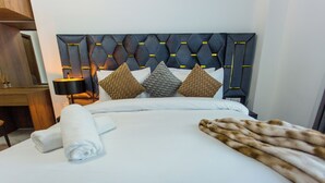 Een net opgemaakt bed met witte lakens, een zachte bontdeken en een hoofdbord met geometrische patronen.