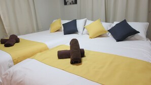 Een hotelkamer met twee bedden, elk met een gele sprei en bruine handdoeken.