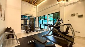 Ein Fitnessstudio mit Trainingsgeräten, Laufband und einer Bank.
