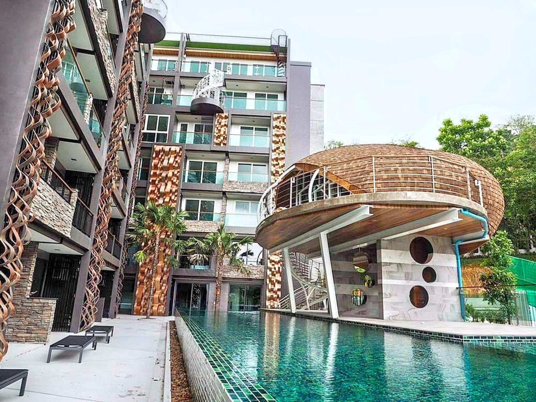 A modern building with a pool, featuring a unique circular structure with a wooden roof and a glass facade.