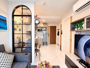 A modern living room with a sofa, a TV, and a dining area with chairs. - A203 - 1 Bedroom Serviced Apartment with Seaview at Ao Nang Beach (Tambon Ao Nang)