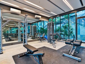A modern gym with various exercise equipment, large windows, and a view of greenery outside. - A203 - 1 Bedroom Serviced Apartment with Seaview at Ao Nang Beach (Tambon Ao Nang)
