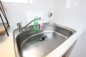 Lavello d'acciaio inossidabile con rubinetto, erogatore sapone e porta sapone.