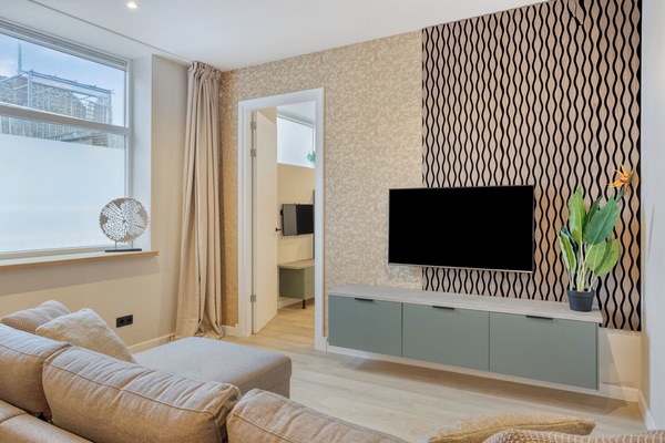 Stylish and serene living room with luxurious wallpaper, natural light, and TV