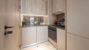 Een compacte keuken met lichte houtkleurige kastjes, een roestvrijstalen oven en een inbouwmagnetron.