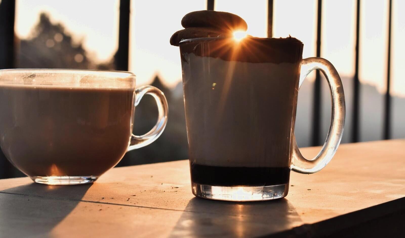 Two coffee mugs on a table with a view of a cityscape in the background.