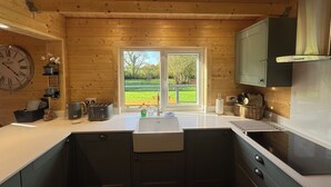 A kitchen with wooden walls, a large window, a sink, and modern appliances. - 3 Bedroom 2 Bath Chalet with hot tub in peaceful countryside close to Exeter (Broadclyst)