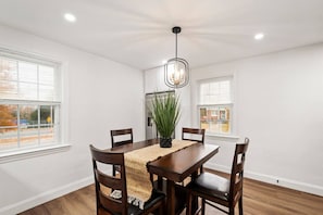 A dining room with a wooden table and chairs, a hanging light fixture, and a potted plant. - Near DC Group Getaway Free Parking + WiFi + Yard (Hyattsville)