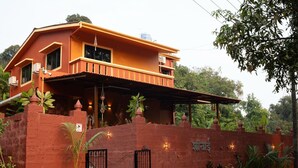 A two-story building with a red exterior, a balcony, and a gated entrance.