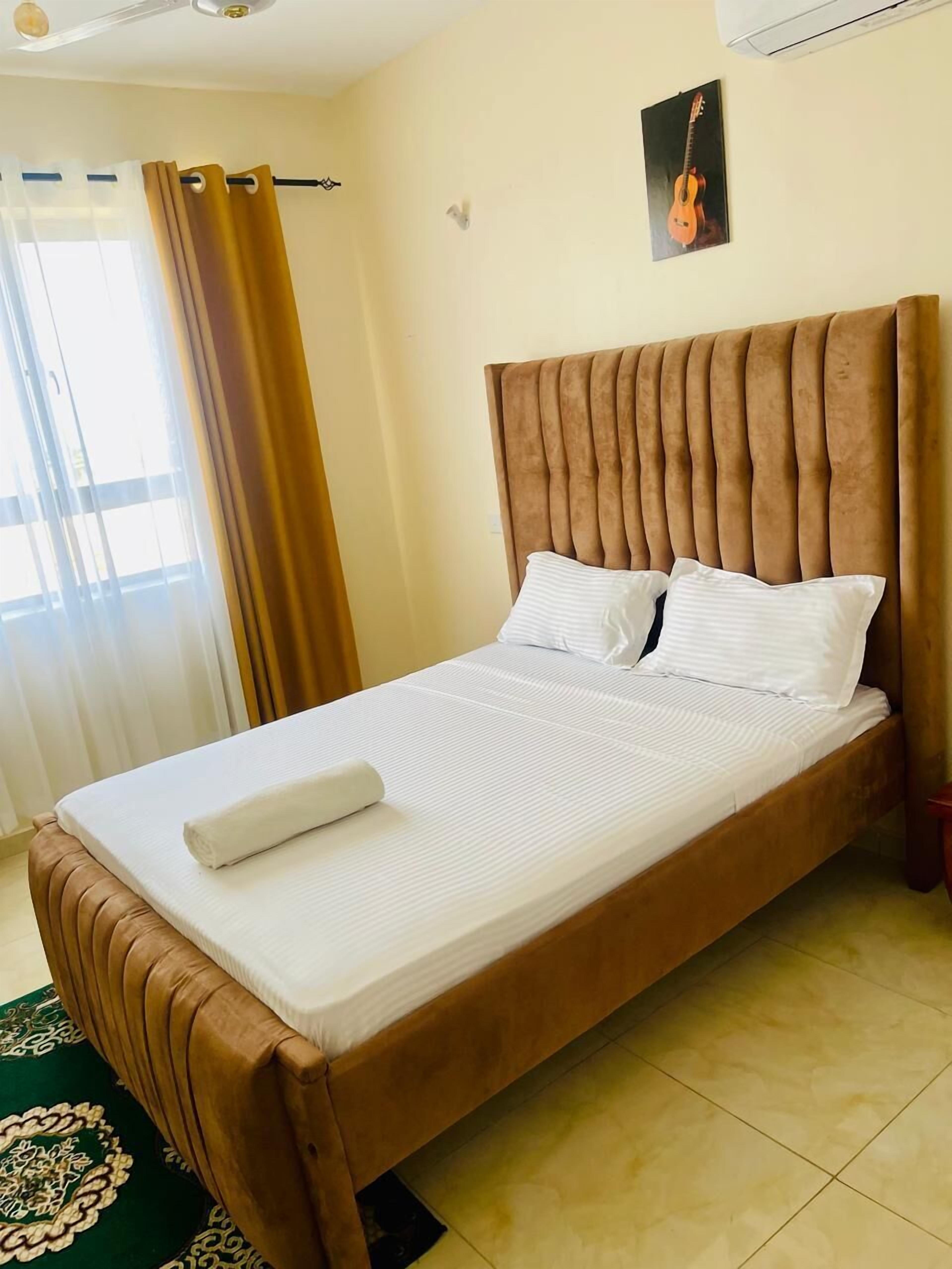 A single bed with a wooden frame and a headboard, a white mattress, and two pillows.