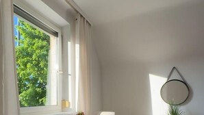 A dining area with a table, chairs, a potted plant, and a wall-mounted mirror. - Spacious Garden Villa for 16 Guests (Vienna)