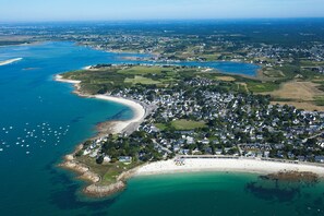 Ett flygbildsbild av en kuststad med en strand, hus och båtar.