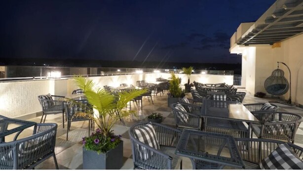 An outdoor patio area with wicker furniture and potted plants. - Su Casa Banquets and Hotel (Vikasnagar)