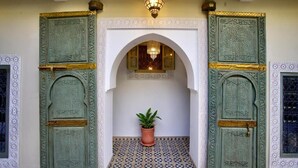 A traditional entrance with ornate green doors, a tiled floor, and a potted plant. - Riad Mazarin des gourmets (Marrakech)
