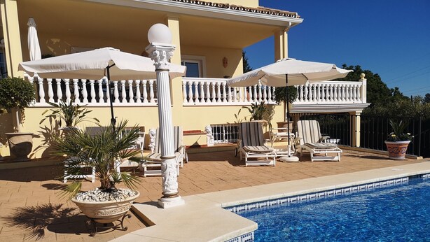 A poolside area with lounge chairs, a white balustrade, and a tiled pool. - Apartment 'Roca' with Sea View, Wi-Fi and Air Conditioning (Estepona)
