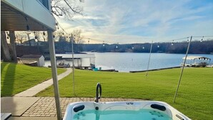 A hot tub with a view of a lake, a covered patio, and a grassy area. - Waterfront Retreat with Hot Tub (Marion)