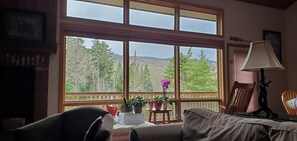 A cozy room with a large window offering a view of a forested mountain range. - 2-bedroom mountain getaway in Bretton Woods with A/C, family-pet friendly (Carroll)