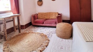 A cozy room with a wooden table, a red sofa, a patterned rug, and a cabinet.