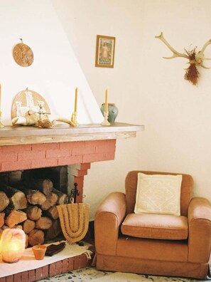 A cozy living room with a fireplace, a leather armchair, and a wall-mounted deer skull. - Nuragic Temple - Unique Accommodations in the Heart of Ancient Sardinia (Esterzili)