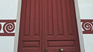 A red door with a brass handle and a decorative top.