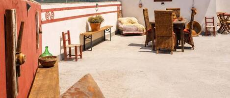 A rooftop terrace with a dining area, chairs, a table, and a view of the mountains.