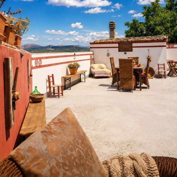 Una terraza en la azotea con comedor, sillas, una mesa y vistas a las montañas.