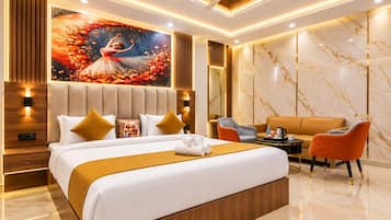 A modern hotel room with a large bed, a seating area with a sofa and chairs, and a decorative wall mural.