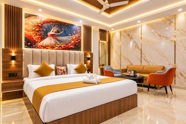 A modern hotel room with a large bed, a seating area with a sofa and chairs, and a decorative wall mural. - Hotel NS Near Delhi Airport (New Delhi)