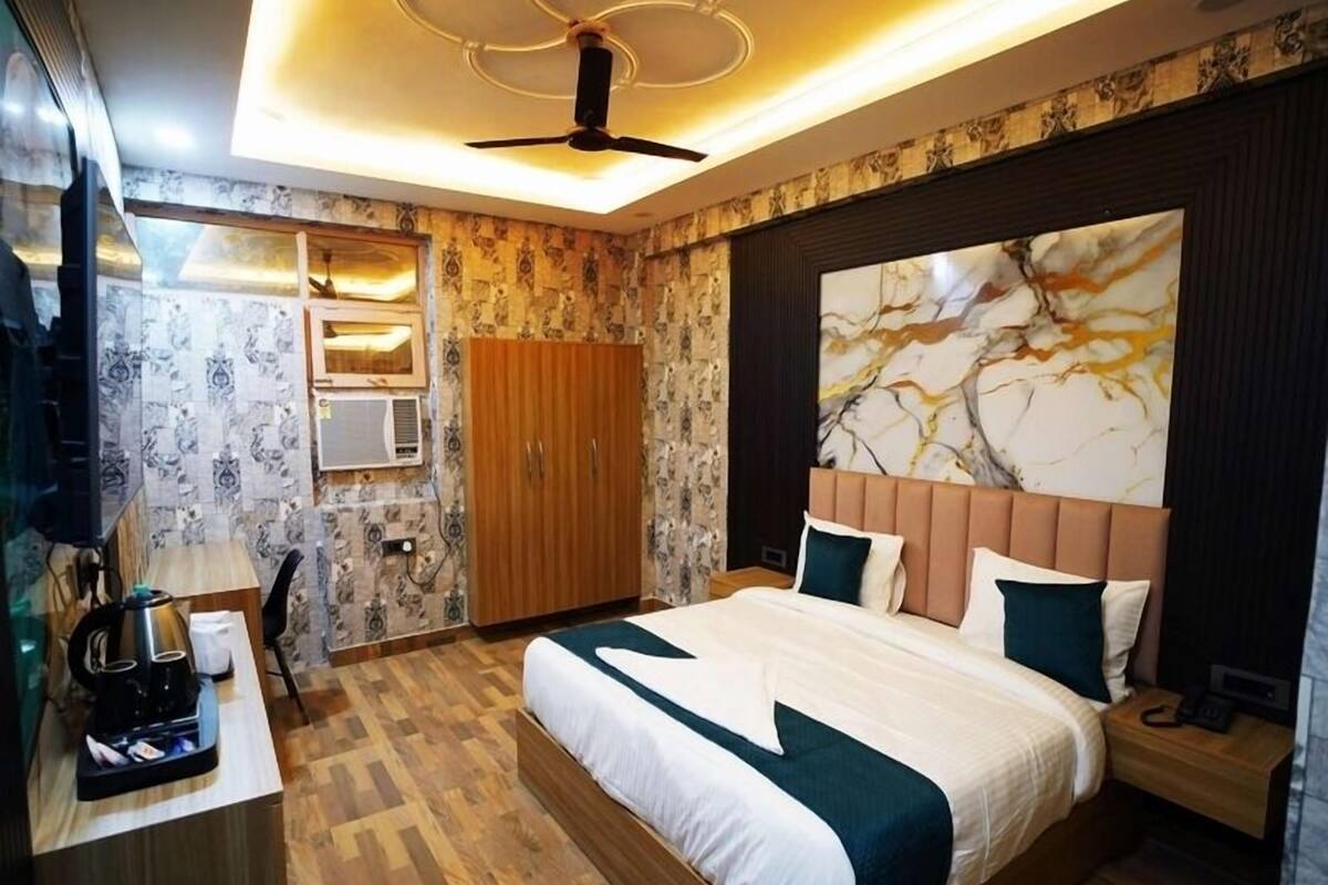 Une chambre d’hôtel moderne dotée d’un grand lit, d’une armoire en bois, d’un bureau avec une machine à café et d’un ventilateur de plafond.