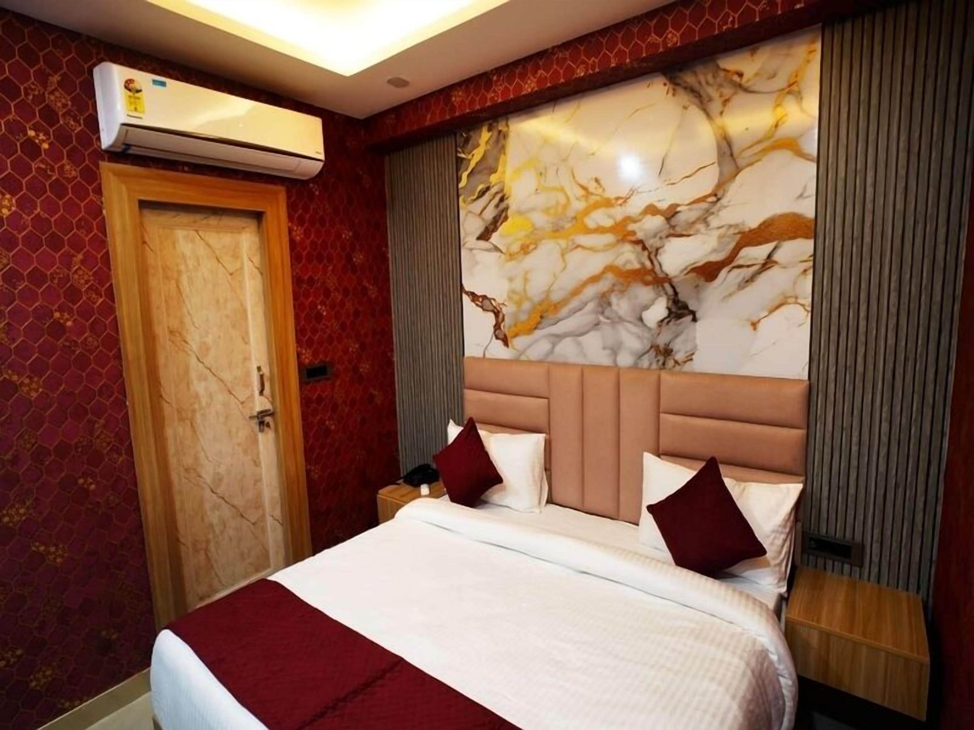 Una habitación de hotel con una cama grande, cabecera de mármol y un equipo de aire acondicionado en la pared.