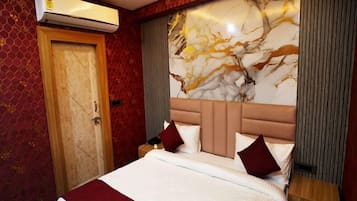 Una habitación de hotel con una cama grande, cabecera de mármol y un equipo de aire acondicionado en la pared.