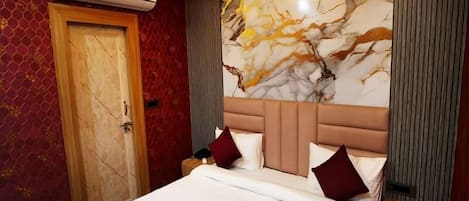 A hotel room with a large bed, a marble headboard, and an air conditioning unit on the wall.