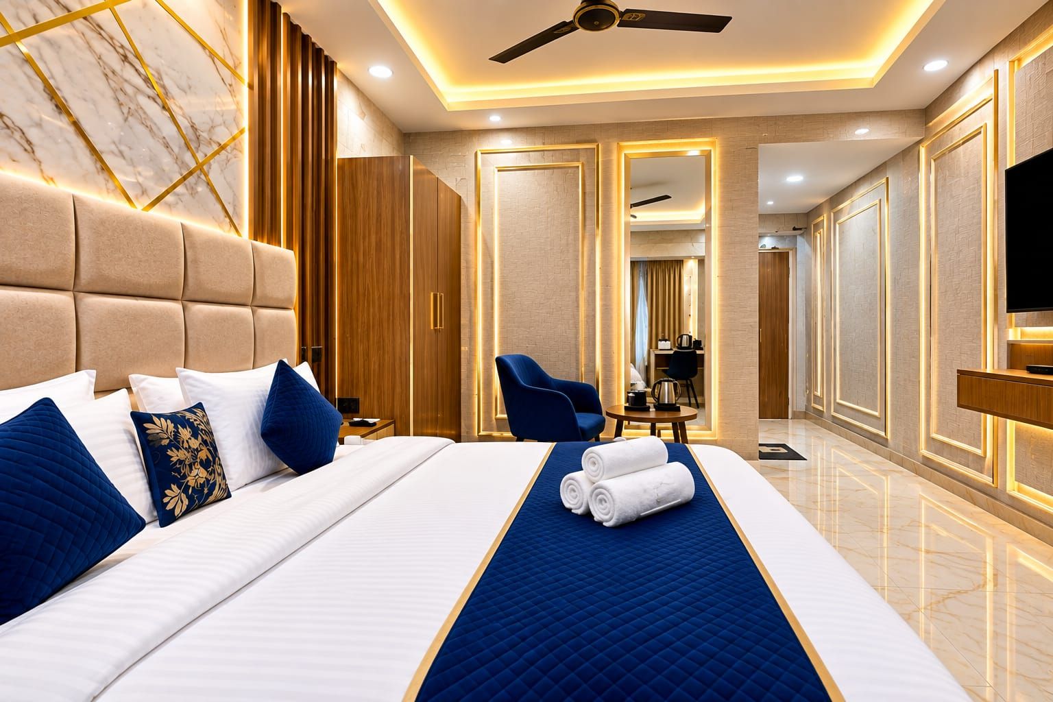 A hotel room with a large bed, a flat-screen TV, a ceiling fan, and a seating area with a table and chairs.
