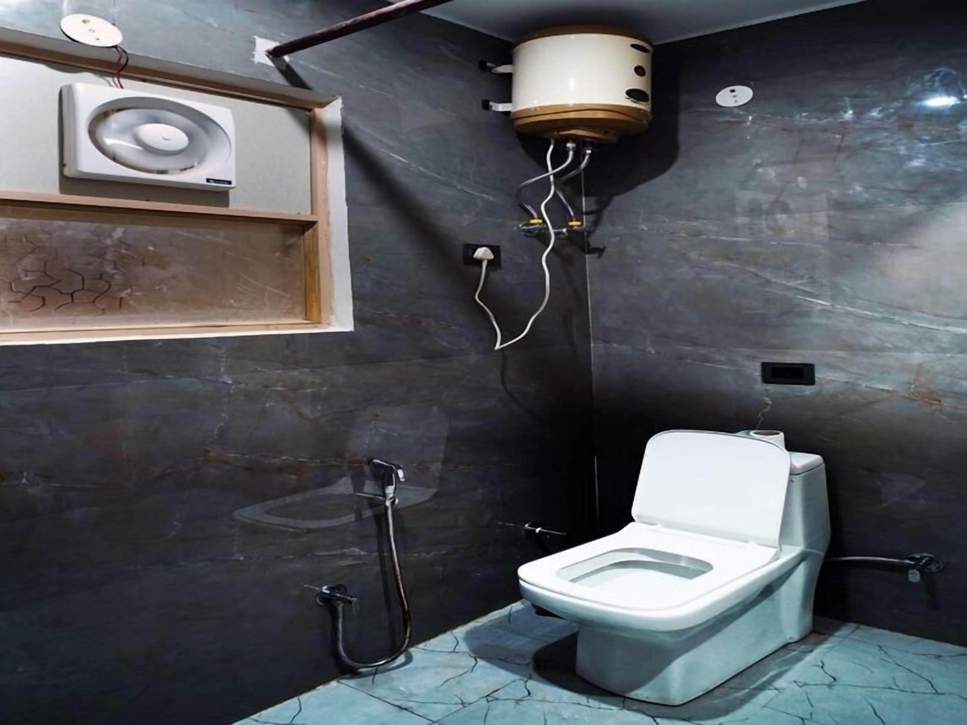 A compact bathroom with a toilet, a shower, and a built-in heater.