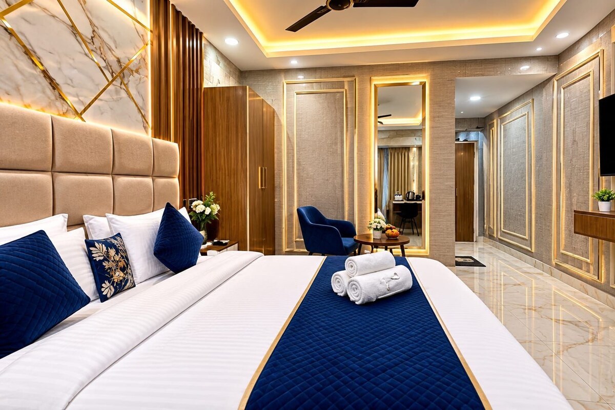 A hotel room with a large bed, a desk, a chair, and a television.