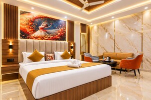 Een moderne hotelkamer met een groot bed, een zithoek met een bank en stoelen, en een decoratief muurschildering.