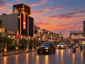 A hotel with a prominent sign, a medical store, and a pharmacy across the street. - Hotel NS Near Delhi Airport (New Delhi)