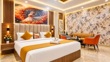 Una habitación de hotel moderna con una cama grande, un área de descanso con un sofá y sillas, un muro decorativo con estampado floral y un ventilador de techo.