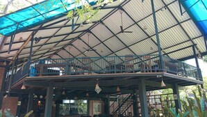A covered outdoor area with a balcony, a staircase, and hanging plants. - Doola River Edge (Udawalawa)