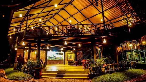 A spacious outdoor area with a covered seating area, a staircase, and a view of the interior. - Doola River Edge (Udawalawa)