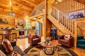 L'intérieur d'une cabane en rondins comprend une cuisine, un coin repas et un escalier.