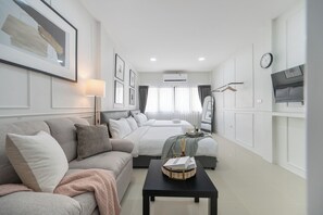 Una habitación de hotel moderna con sofá, cama, televisor y escritorio.