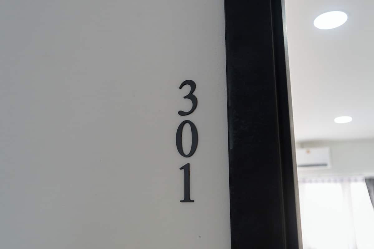 A close-up of a white wall with the number "301" in black, indicating a room or office number.