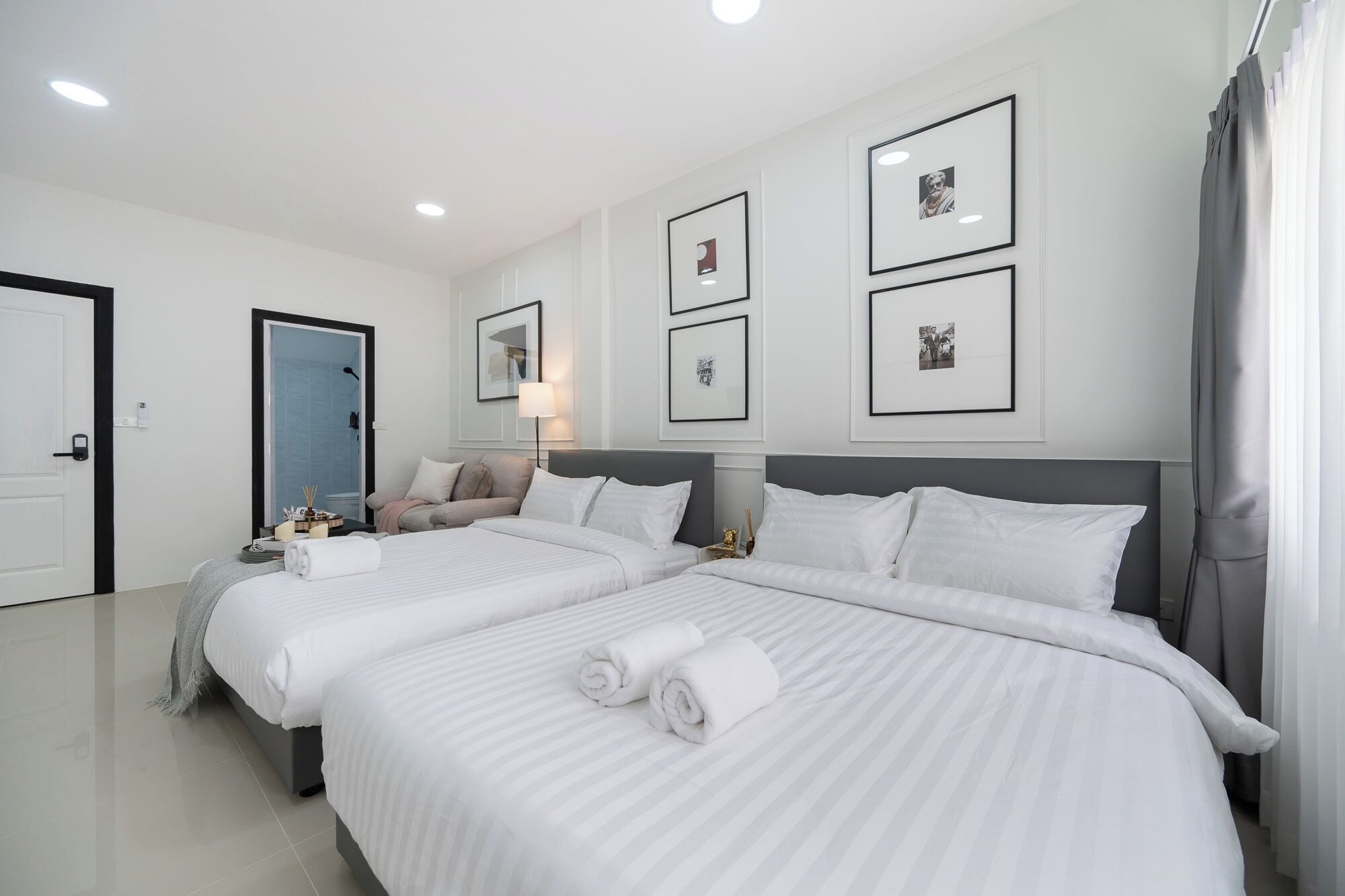 A hotel room with two beds, a sitting area with a sofa, a small table, and framed pictures on the wall.