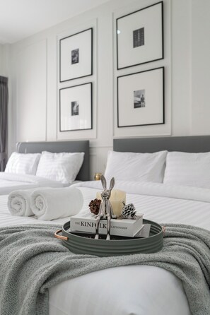 A neatly made bed with white linens, a grey throw blanket, and a tray with a book titled "The Kinfolk Relationship" and a silver bunny figurine. - Arun Sa Wad - Chinatown (Bangkok)