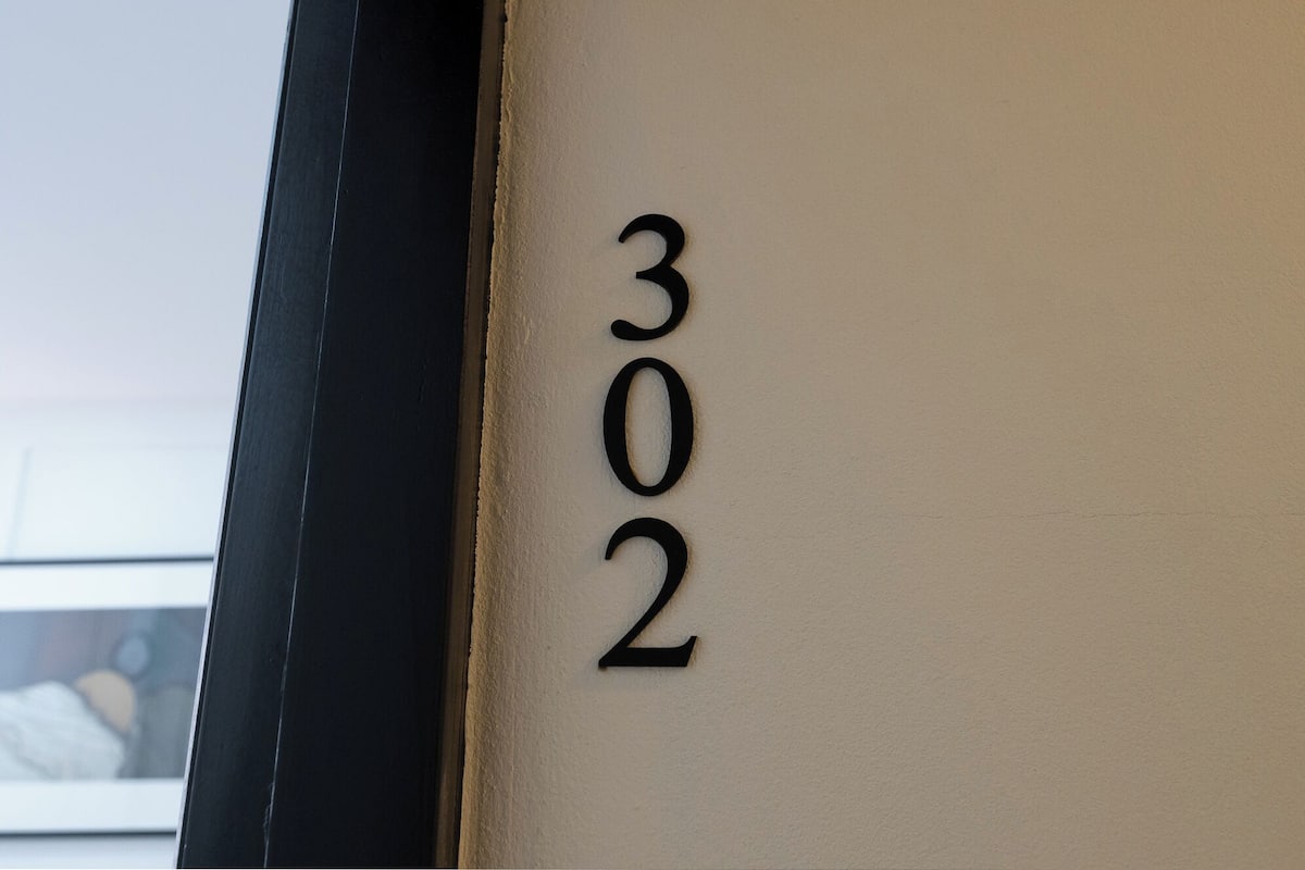 A close-up of a wall with the number "302" indicating a room number.