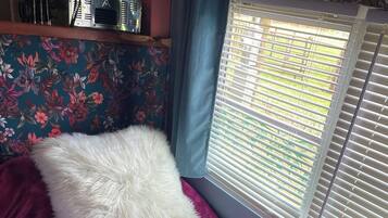 A small bed with a white fluffy pillow and a purple bedspread.
