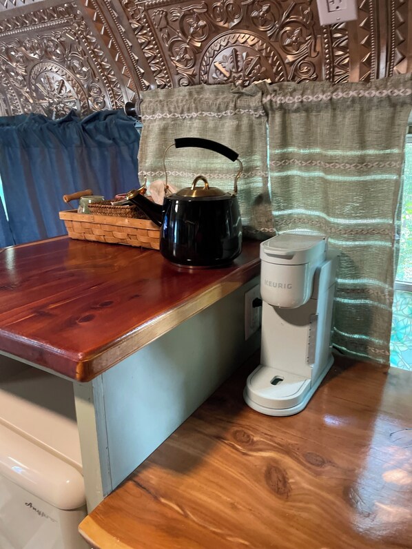 A kitchen counter with a kettle, a coffee maker, and a woven basket.