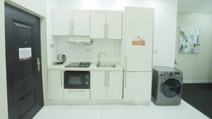 Een kleine keuken met witte kasten, een inbouwoven, een spoelbak en een wasmachine.