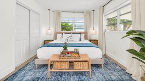 Un dormitorio con cama, mesitas de noche, cortinas en la ventana y vistas al exterior.